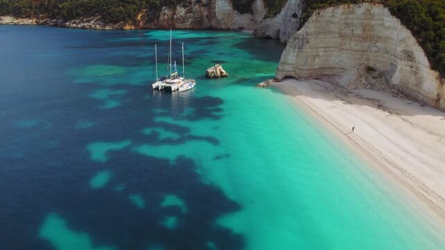 Anchored sailboats resting in a vivid turquoise bay surrounded by white cliffs on Fteri beach on Kefalonia coast