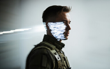 serious young man in tactical gear with a digital pixelated light glitch mask over half of his face on a clean neutral gray background with tech theme.