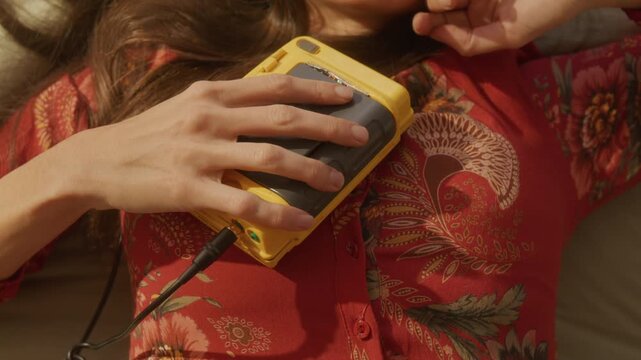 Trendy dreamcore woman listening to portable cassette player on bed stretches to get up
