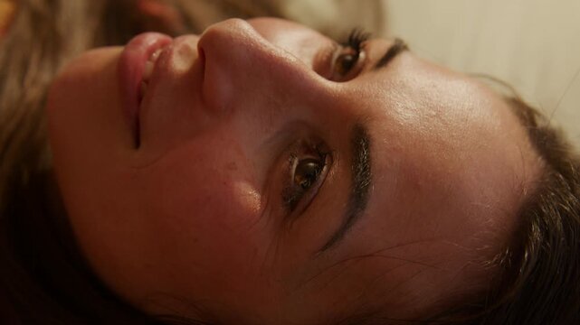 Young Woman Dreamcore - Listing to music laying in bed smiling - close up