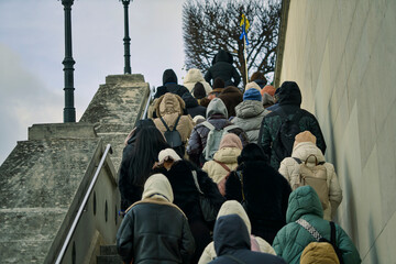 Diverse crowd of people ascending a massive concrete exterior