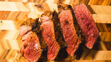 Topside beef roast coated in flavorful rub, roasted rare and juicy inside, presented on a wooden...