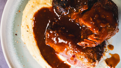 Beef shin with bone served on a plate with creamy mashed potatoes. Tender, fall-off-the-bone meat,...