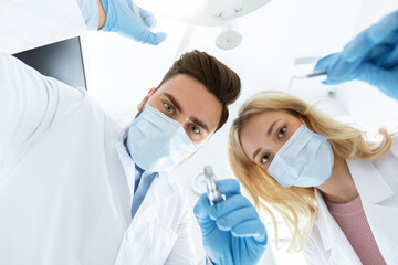 Two dentists young caucasian man and woman in face masks and rubber gloves doing treatment, turning...
