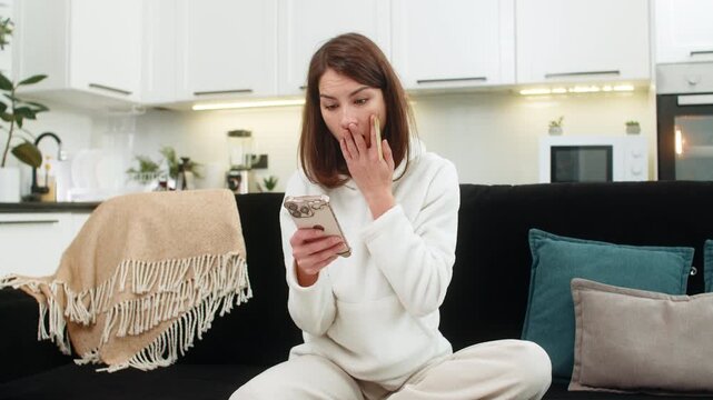 Young woman at home tries online buy gets payment fail and card block notice feels panic checks account. Caucasian girl on sofa suspects fraud calls support locks card starts dispute and waits reply
