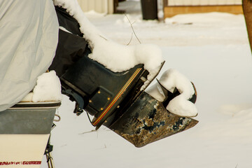 An outboard boat motor covered in snow during winter