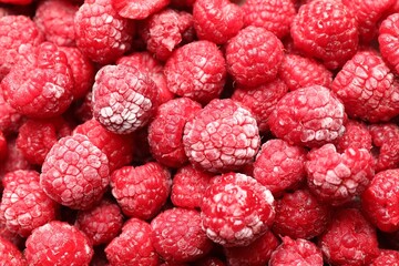 Frozen ripe raspberries as background, top view