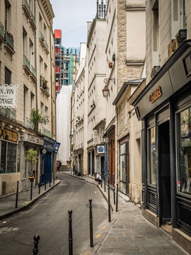 PARIS, FRANCE - JUNE 22, 2025: A view down a narrow, empty cobblestone street lined with tall historic buildings in the Le Marais district of Paris, in the historical center of the french capital.