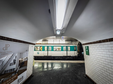 PARIS, FRANCE - JUNE 22, 2025: A view of a metro train arriving at a tiled platform in a Paris Metro station. Operated by RATP, metro de paris is the main transit system of the city.