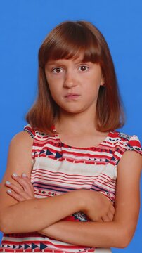 Cheerful funny young brunette school lady showing tongue making faces at camera, fooling around, joking, aping with silly face, teasing, bullying, abuse. Preteen female child kid on blue background