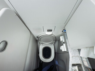 High-angle view of a compact lavatory inside a commercial airplane during a flight, some airplaine toilets. The small restroom features a toilet bowl, sink, and standard amenities for passengers.