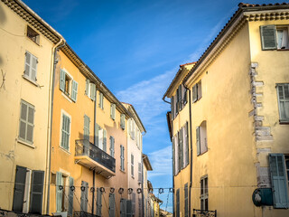 Traditional yellow facades and shutters of residential buildings in Vieux Hyeres. The historic architecture features warm walls and green wooden shutters typical of Cote D'azur and provence, in France