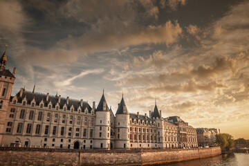 Conciergerie by the Seine river at sunset illuminated by the warm golden light of the evening. The historic courthouse, former prison is a major attraction on Ile de la Cite.