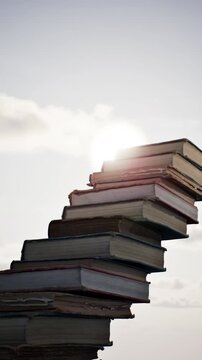 Concept idea stack of books on sky sun set dawn beautiful background. 3D animation. 4K.	
