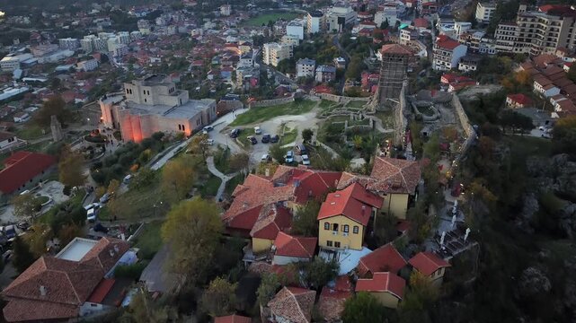 Aerial video of Kruj&euml; Castle, Watch Tower, and cliffside houses blending with the modern town at twilight.