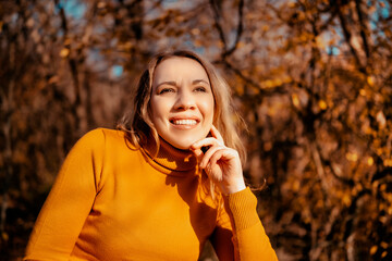 Close up portrait of smiling woman in autumn forest, warm sunlight, outdoor lifestyle, seasonal...