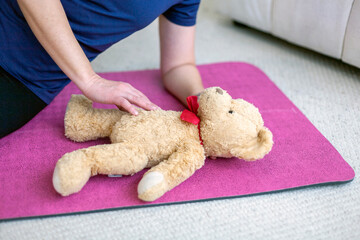 CPR training, child safety practice, emergency preparedness, teddy bear model, caregiving skills, parental care concept, baby expectation, nurturing instinct, gentle touch, caregiver readiness, family