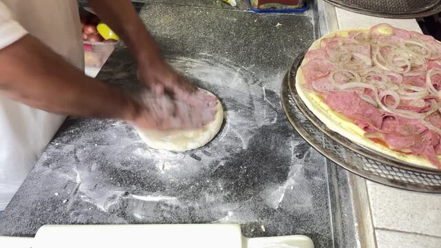 Opening pizza dough by hand in Brazil