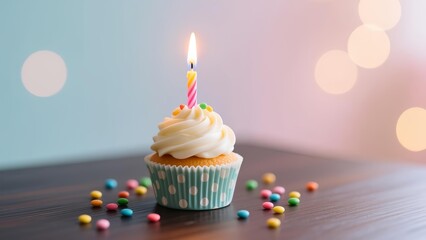 A single cupcake with a lit candle and colorful sprinkles on a wooden table