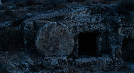 Obraz premium Open empty cave tomb with large round stone rolled away at dawn representing resurrection of Jesus Christ