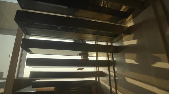 Man walks down modern steel stairs with striped light patterns, minimalist luxury interior