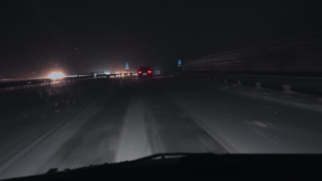 Longhaul truck maintains steady speed amidst snow and blinding oncoming headlamps during fierce winter storm