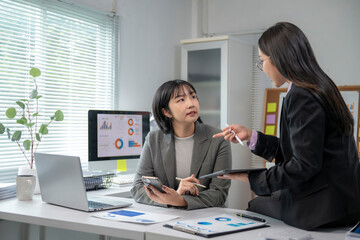 Businesswomen discussing financial charts and data analysis in office meeting
