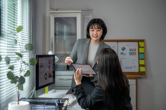 Businesswomen discussing financial charts on digital tablet in office meeting - Powered by Adobe