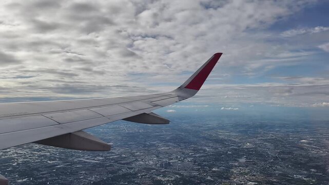 The plane was flying over Bangkok. Aerial view of the Bangkok city the wing tips of the airplane with the clear blue sky.
