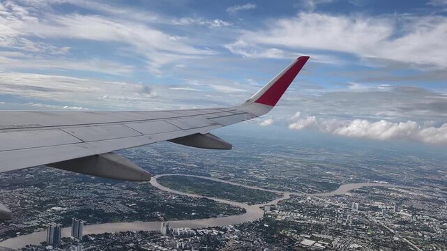 The plane was flying over Bangkok. Aerial view of the Bangkok city the wing tips of the airplane with the clear blue sky.
