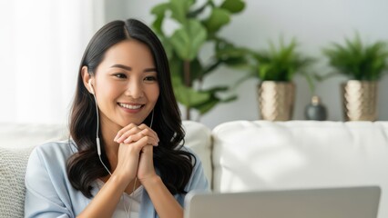 Young woman smiling while using laptop on a white couch in a bright living room