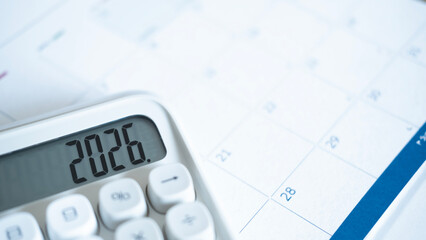 Minimal workspace with calculator on a calendar marked 2026, representing financial planning,...
