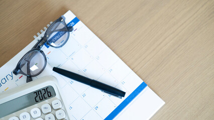 Clean desk workspace featuring calendar, pen, and calculator, representing monthly budgeting, financial analysis, and goal setting for year 2026.