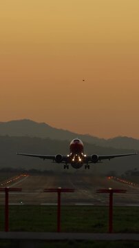 Vertical front low angle view of a commercial airplane taking off at sunset