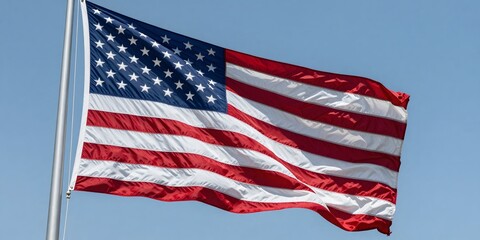 Fototapeta premium American flag waving proudly against a clear blue sky on a sunny day