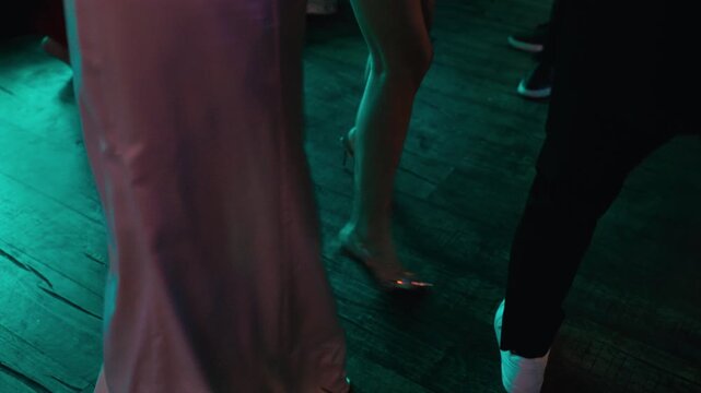 Capturing dynamic dance with high heels across textured flooring illuminated by vivid green light