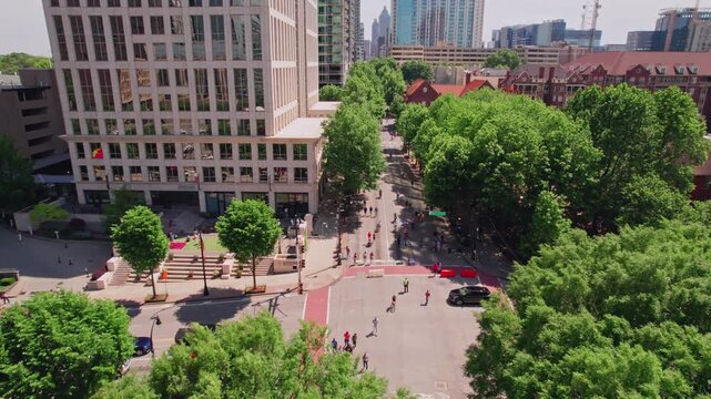 An aerial tilting up above the green tree canopy over Peachtree Street during a Streets Alive urbanism event in Atlanta, with bikers and pedestrians enjoying a bright summer day in the Georgia city.