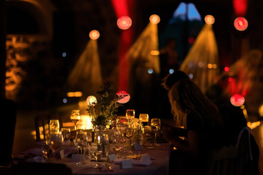 Candlelit luxury dinner table at an elegant evening event with wine glasses, floral centerpiece, and dramatic ambient lighting, creating a romantic, cinematic atmosphere.