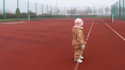 Girl looking into a foggy tennis court dreaming to become the best tennis player in the future.