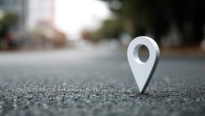 Metallic map marker stands prominently on a textured asphalt road, blurred background