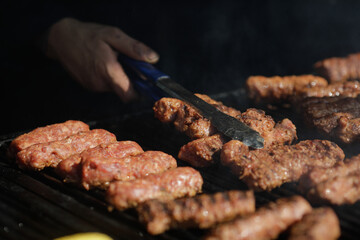 Romanian traditional mici (mititei or rolled minced meat) on an outside charcoal metal grill.