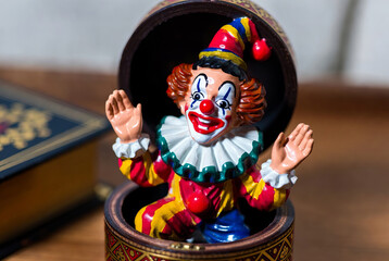 The box suddenly opens and a clown figure suddenly jumps out of it, frightening everyone around.