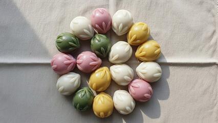Colorful songpyeon rice cakes arranged in circular pattern on white linen fabric for korean chuseok harvest festival