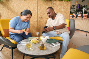 Friends enjoy snacks and drinks while taking pictures in a cafe during afternoon time