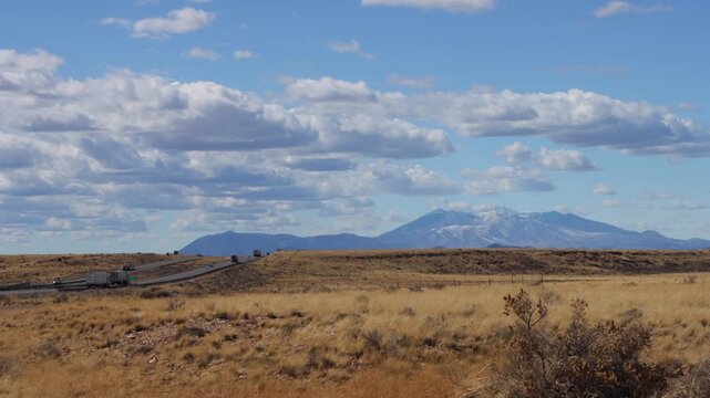 View of traffic moving on I-40 and the San Francisco Peaks near Flagstaff, Arizona, with spectacular white clouds in blue sky