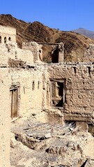 Cliffside Village With Ancient Dwellings, Archaeologist Surveys Historic Adobe Village On Elevated Cliffside, Panoramic Scene Of Ancient Adobe Homes Built On Steep Hillside With Erosion Features