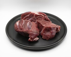 Fresh raw beef meat pieces on black plate isolated on white background for cooking