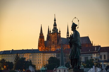 Czech Republic, Prague September 6, 2025, the statue of John of Nepomuk on the Charles Bridge in Prague, with the castle on the Hradčany in the background and the setting sun