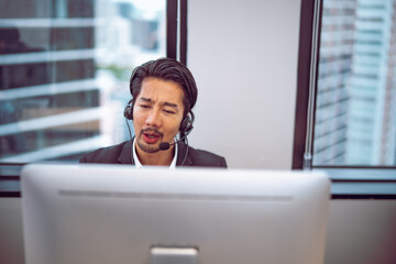 Male office worker providing online support through headset, focused posture reflecting responsibility and efficient workflow