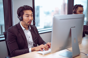 Male employee at help desk station using headset, modern office environment emphasizing productivity and customer care